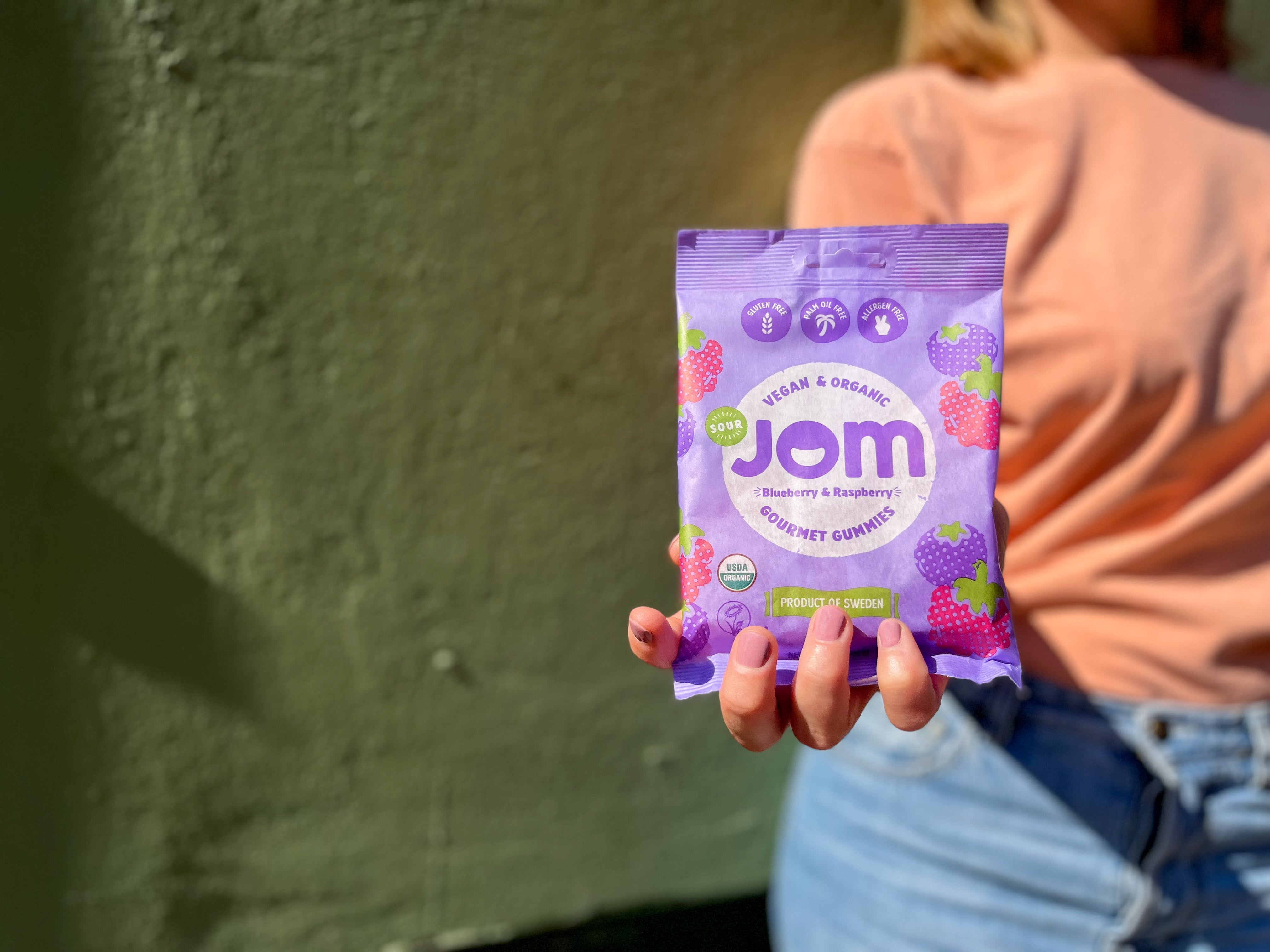 Organic Candy JOM Sour Blueberry and Raspberry Vegan Gummies USA Holding Bag in Hand